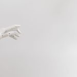 Mão robótica minimalista estendida sobre fundo branco.